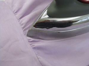 Press gathers towards seam, spreading them with the point of the iron.