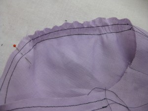 Carefully smooth easing back along the ease row nearest the seam line.  The outer edge will remain fluted while the seam line area fits the armhole perfectly.