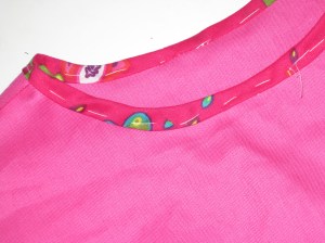 Once trim has been rolled over edge, tack in place before hand stitching