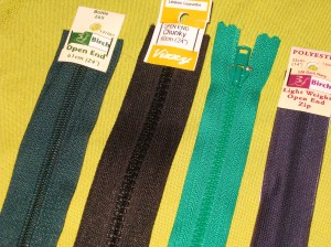A selection of open-end zips - Left to right are large plastic teeth; wide chunky teeth; narrow teeth; open end invisible zip.