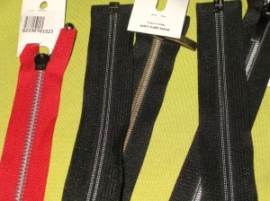 A selection of open-end zips - Left to right are large plastic teeth; wide chunky teeth; narrow teeth; open end invisible zip.