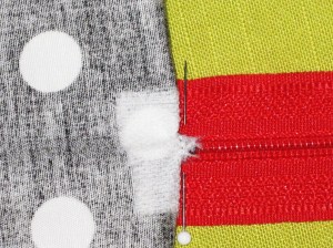 Fold fabric at the bottom of the zipper up over the teeth to reveal the triangle at the base of the zipper. Stitch across.