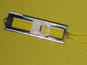 All buttonhole feet have prongs at either end. Wrap thicker thread around the back prong and fasten in the grooves at the opposite end. Stitch the button hole as usual - over the cord. When buttonhole is complete, pull the cord ends and use a hand needle to feed them to the back; trim the tails.