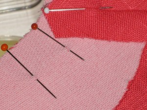 Pin facing to garment. To prevent slippage and make it easier to avoid puckers, pin at right angles to the seam and take a small bite with the pin right around where the seam line lies.