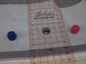Use ruler to align grainline and weights to keep the grain line in place while pinning.