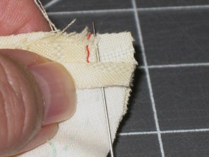 Fold back upper seam allowance and position a pin so that it lies right against, but not through, tap. This pin will help with positioning the machine needle to commence stitching.