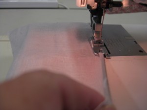 Stitch the first section of the hem in place; leaving the needle in the hem, carefully roll the fabric into the curl of the foot - keeping the fabric pulled slightly to the right in the same direction as the marking on the foot.