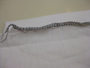 Hem stitches between hem and garment and positioned just at the lower edge of overlocking.